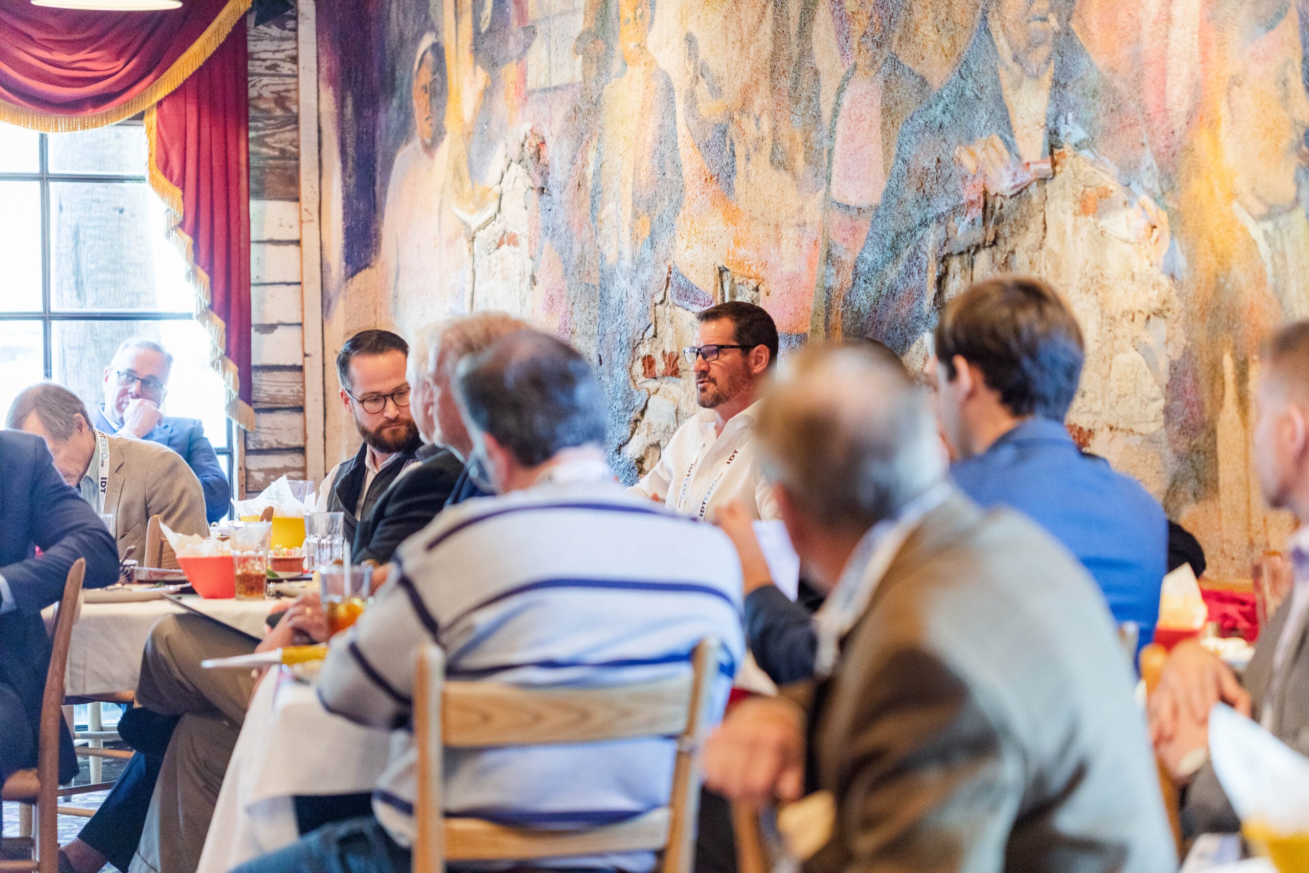 Members of the Capital Advisors group sit at dining tables in a banquet hall and have discussions.